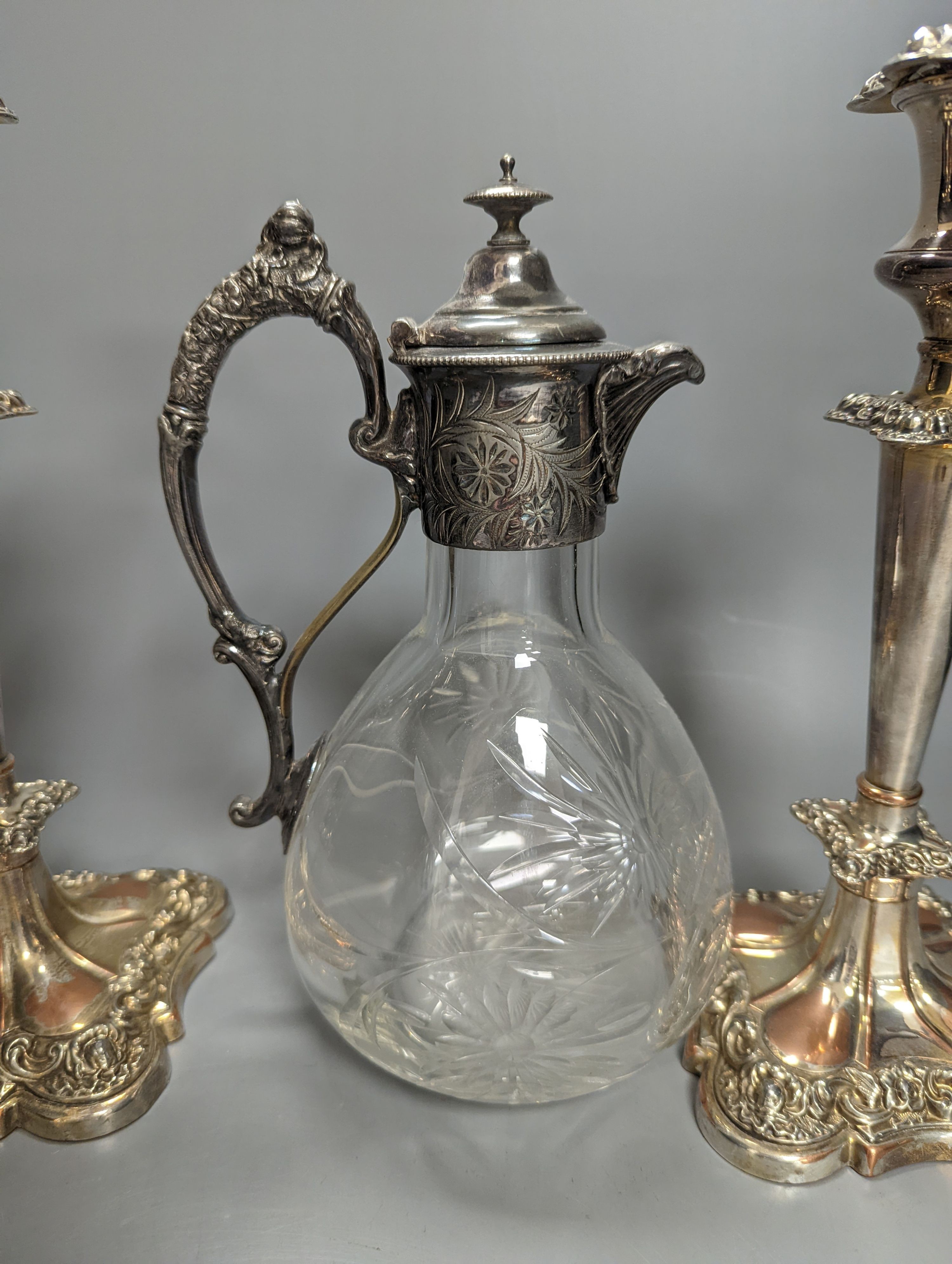 A Victorian electroplate mounted glass Claret jug, 23.5cm high and a pair of candlesticks